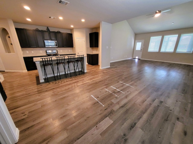 24703 Allori Ct, Katy, TX 77493 - kitchen featuring stainless steel microwave, open floor plan, baseboards, recessed lighting, and lofted ceiling