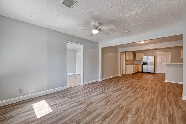 10613 Buffum St, Houston, TX 77051 - unfurnished living room with light wood-style floors, a ceiling fan, baseboards, and a textured ceiling