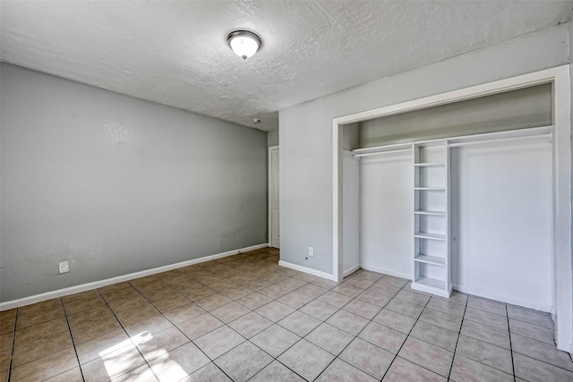 10613 Buffum St, Houston, TX 77051 - unfurnished bedroom with a closet, light tile patterned floors, a textured ceiling, and baseboards
