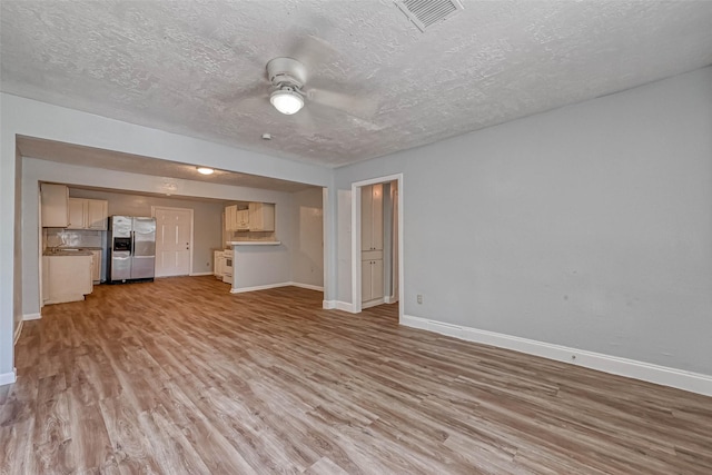 10613 Buffum St, Houston, TX 77051 - unfurnished living room featuring light wood-type flooring, baseboards, ceiling fan, and a textured ceiling