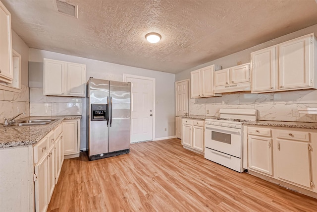 10613 Buffum St, Houston, TX 77051 - kitchen with stainless steel fridge with ice dispenser, white range with gas stovetop, a sink, light wood finished floors, and under cabinet range hood