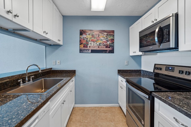 8952 Wilcrest Dr Unit 8952, Houston, TX 77099 - kitchen with appliances with stainless steel finishes, a sink, baseboards, white cabinetry, and tasteful backsplash