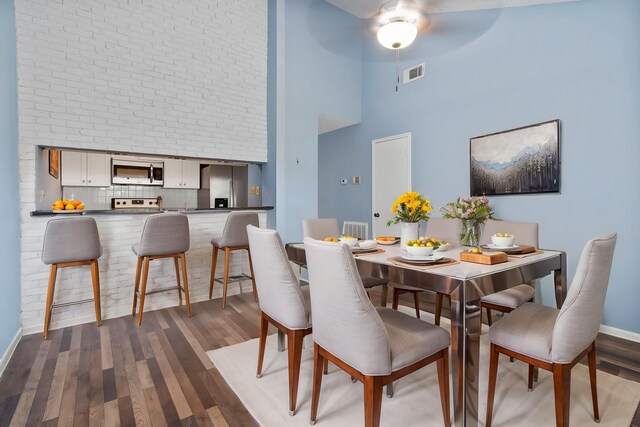 8952 Wilcrest Dr Unit 8952, Houston, TX 77099 - dining area featuring a towering ceiling, dark wood-style floors, a ceiling fan, and baseboards