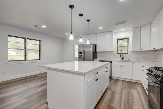229 Burkett St, Richwood, TX 77531 - kitchen featuring stainless steel appliances, a center island, light wood finished floors, backsplash, and recessed lighting