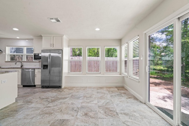 12006 Acorn Oak St, The Woodlands, TX 77380 - kitchen with appliances with stainless steel finishes, white cabinetry, tasteful backsplash, light stone countertops, and recessed lighting