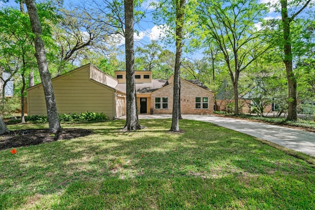 12006 Acorn Oak St, The Woodlands, TX 77380 - mid-century home with a front yard, concrete driveway, and brick siding