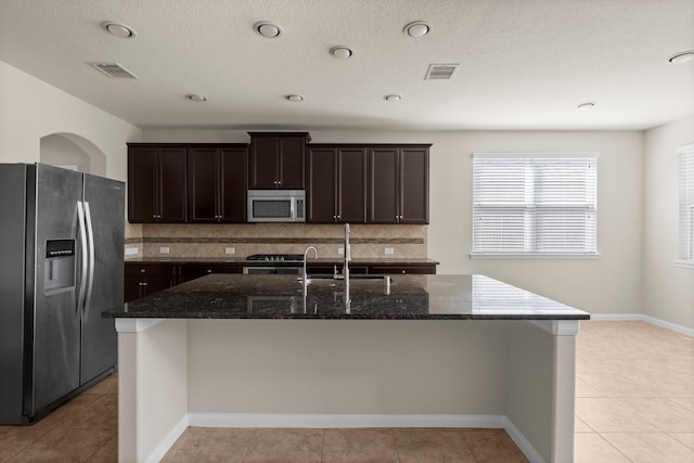 18115 Fernwood Bend Dr, Tomball, TX 77377 - kitchen with stainless steel appliances, a sink, dark brown cabinetry, decorative backsplash, and dark stone counters