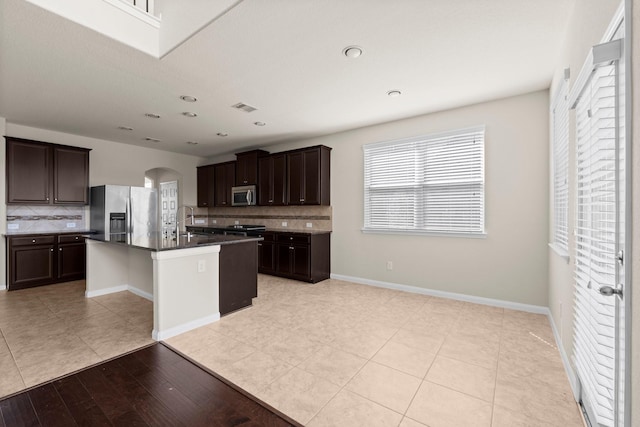 18115 Fernwood Bend Dr, Tomball, TX 77377 - kitchen with stainless steel appliances, arched walkways, decorative backsplash, dark brown cabinets, and recessed lighting