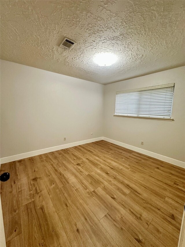 11807 Monticeto Ln, Meadows Place, TX 77477 - empty room with wood finished floors, a textured ceiling, and baseboards