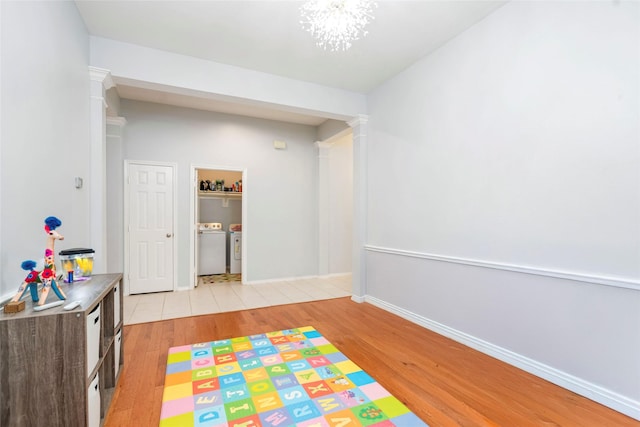 3510 Brookstone Ct, Pearland, TX 77584 - rec room featuring washing machine and dryer, light wood-style flooring, ornate columns, and a chandelier