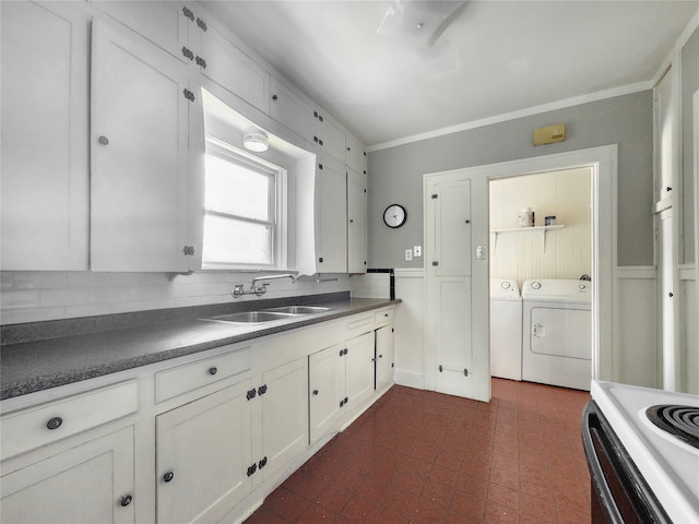 1634 Castle Ct, Houston, TX 77006 - kitchen featuring a sink, washer and dryer, dark countertops, white cabinets, and crown molding