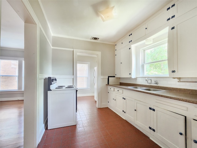 1634 Castle Ct, Houston, TX 77006 - kitchen featuring a sink, white electric range oven, backsplash, white cabinets, and ornamental molding