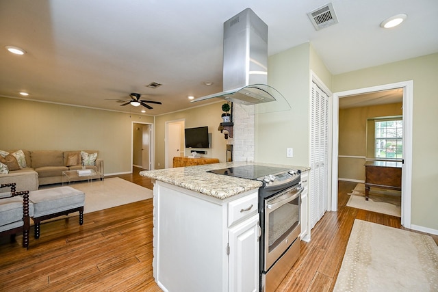 2730 Manila Ln, Houston, TX 77043 - kitchen featuring stainless steel electric range, island range hood, a ceiling fan, light wood-type flooring, and white cabinetry