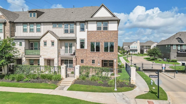 9423 Towne Lake Pkwy, Cypress, TX 77433 - townhome / multi-family property with a gate, a fenced front yard, a residential view, board and batten siding, and stone siding