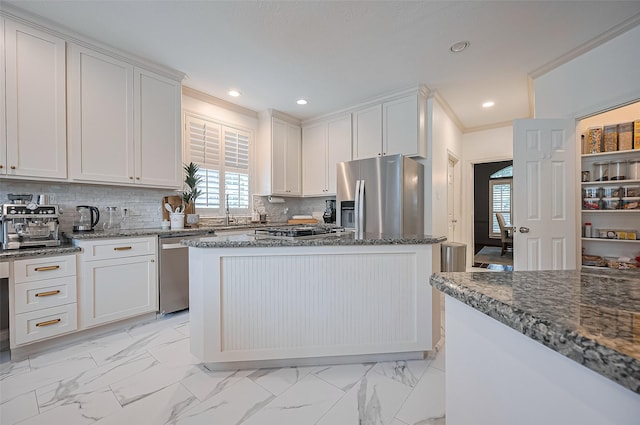 1942 Crisfield Dr, Sugar Land, TX 77479 - kitchen featuring appliances with stainless steel finishes, light marble finish floors, dark stone countertops, white cabinets, and ornamental molding