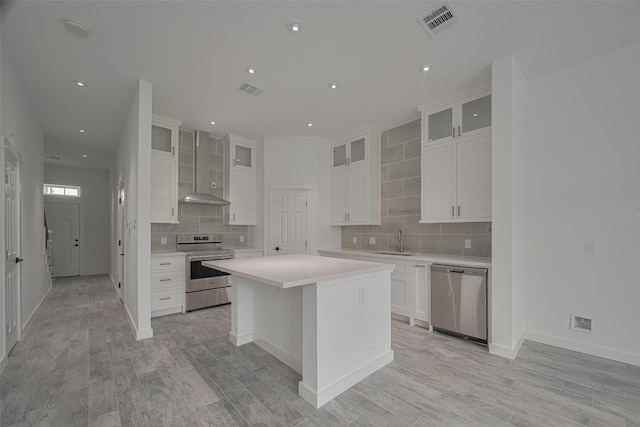 4116 Alvin St, Houston, TX 77051 - kitchen featuring stainless steel appliances, wall chimney range hood, decorative backsplash, a center island, and light countertops