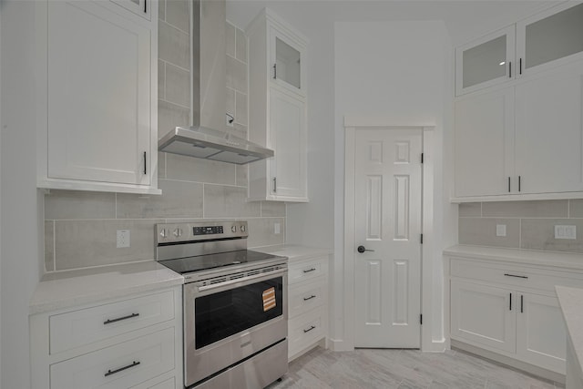 4116 Alvin St, Houston, TX 77051 - kitchen featuring stainless steel electric range, wall chimney range hood, tasteful backsplash, white cabinetry, and glass insert cabinets