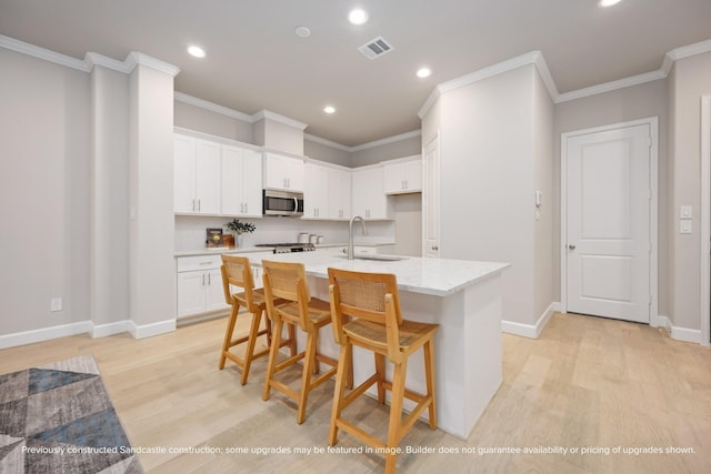 833 Fisher St Unit E, Houston, TX 77018 - kitchen with stainless steel microwave, light wood finished floors, a sink, recessed lighting, and ornamental molding