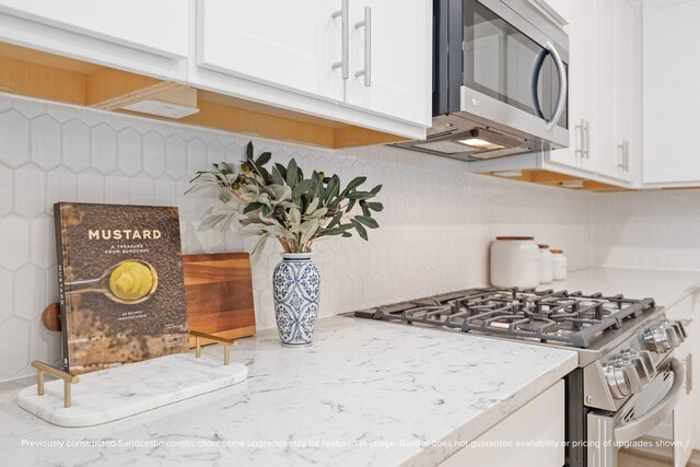 833 Fisher St Unit E, Houston, TX 77018 - kitchen featuring stainless steel appliances, backsplash, white cabinetry, and light stone counters