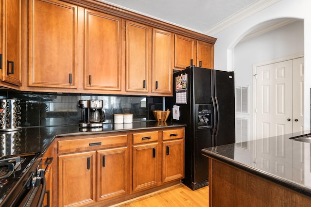 1765 Aden Dr, Houston, TX 77003 - kitchen featuring black fridge with ice dispenser, arched walkways, brown cabinets, range with gas stovetop, and crown molding