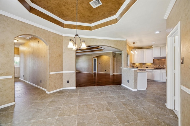 22611 Pineleigh Ct, Tomball, TX 77375 - kitchen with arched walkways, open floor plan, a raised ceiling, light tile patterned floors, and white cabinets