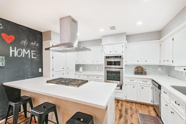 20002 18th Fairway Dr, Humble, TX 77346 - kitchen featuring island exhaust hood, appliances with stainless steel finishes, light wood-style floors, white cabinetry, and recessed lighting