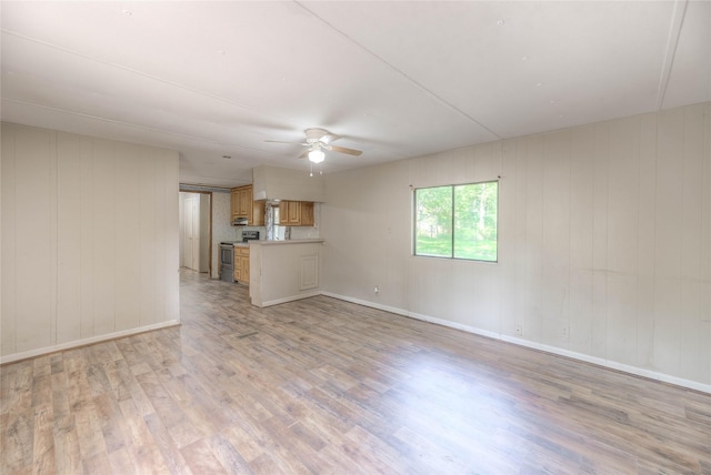 330 Oak Tree Dr, Point Blank, TX 77364 - unfurnished living room with ceiling fan, light wood-type flooring, baseboards, and wood walls