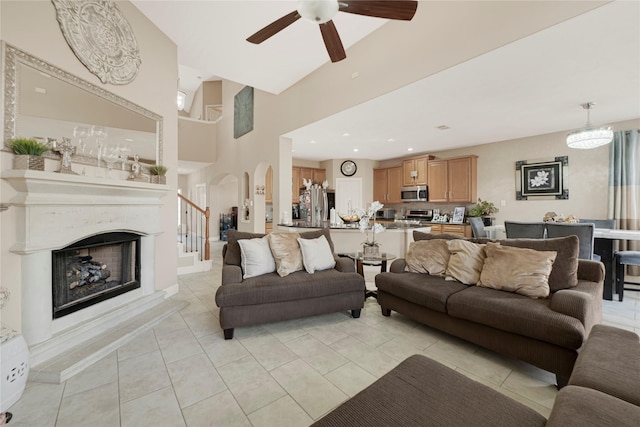 16946 Creek Mountain Dr, Houston, TX 77084 - living area featuring arched walkways, a ceiling fan, a fireplace with raised hearth, light tile patterned floors, and a towering ceiling