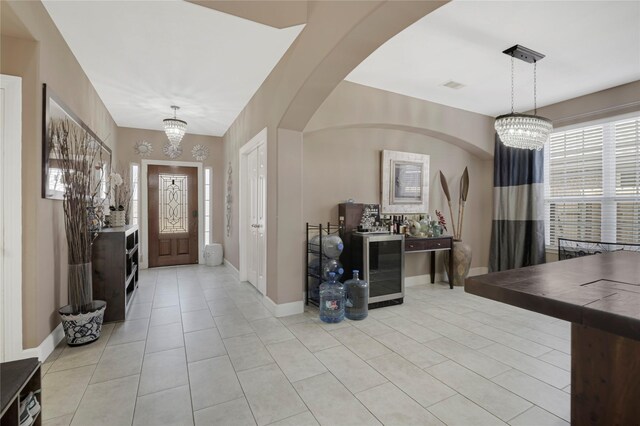 16946 Creek Mountain Dr, Houston, TX 77084 - entrance foyer featuring a chandelier, light tile patterned flooring, beverage cooler, baseboards, and arched walkways