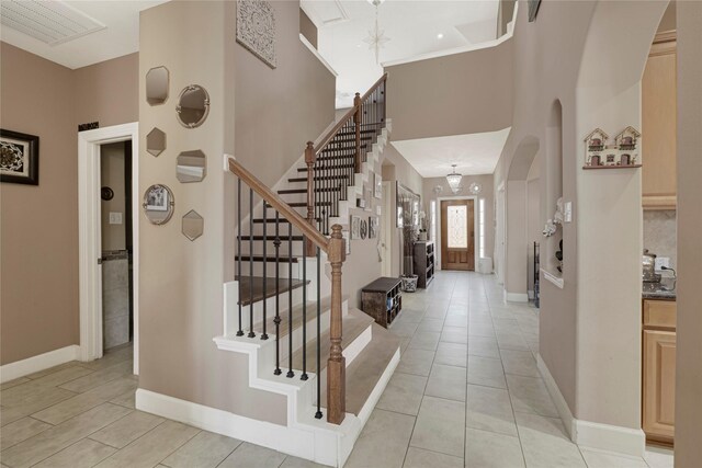 16946 Creek Mountain Dr, Houston, TX 77084 - foyer entrance featuring stairs, arched walkways, baseboards, light tile patterned floors, and a towering ceiling
