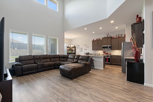 25718 Balsamwood Dr, Tomball, TX 77375 - living room with a high ceiling, light wood-type flooring, recessed lighting, and a chandelier