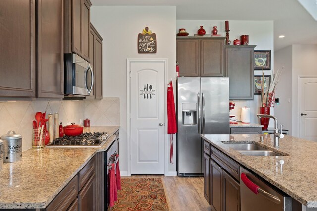 25718 Balsamwood Dr, Tomball, TX 77375 - kitchen featuring appliances with stainless steel finishes, backsplash, light wood-type flooring, light stone counters, and recessed lighting
