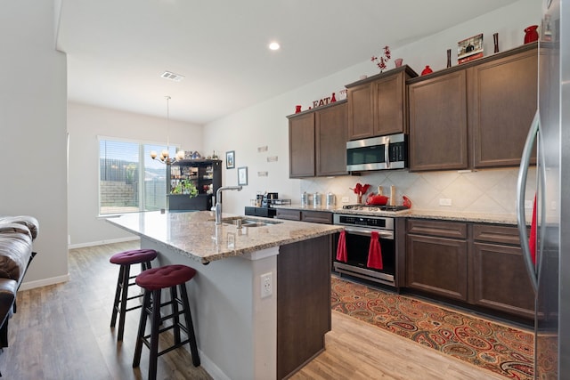 25718 Balsamwood Dr, Tomball, TX 77375 - kitchen featuring stainless steel appliances, a chandelier, light wood finished floors, backsplash, and recessed lighting