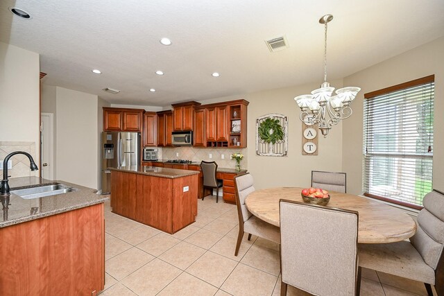 20803 Twisted Leaf Dr, Cypress, TX 77433 - kitchen with appliances with stainless steel finishes, a kitchen island, tasteful backsplash, brown cabinetry, and plenty of natural light