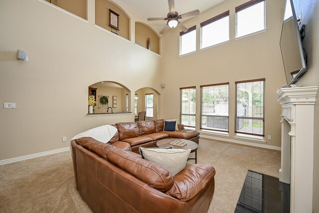 20803 Twisted Leaf Dr, Cypress, TX 77433 - living room featuring carpet floors, a ceiling fan, a towering ceiling, arched walkways, and a fireplace with flush hearth