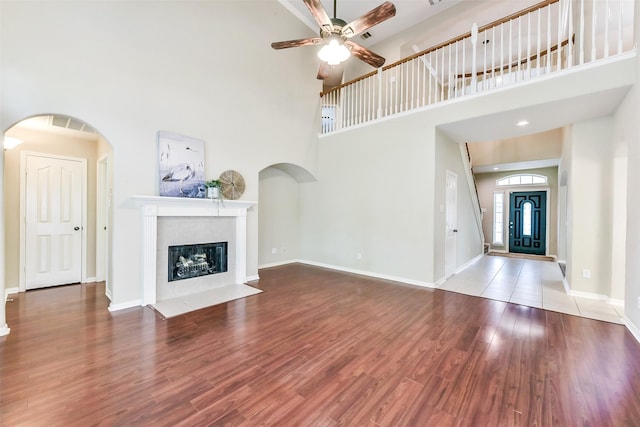 2231 Water Way, Seabrook, TX 77586 - unfurnished living room featuring wood finished floors, a ceiling fan, a fireplace with flush hearth, a high ceiling, and arched walkways