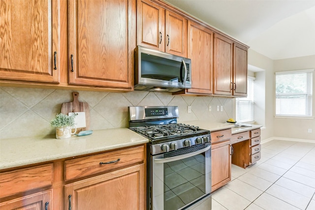 2231 Water Way, Seabrook, TX 77586 - kitchen featuring stainless steel appliances, tasteful backsplash, light tile patterned floors, and brown cabinetry