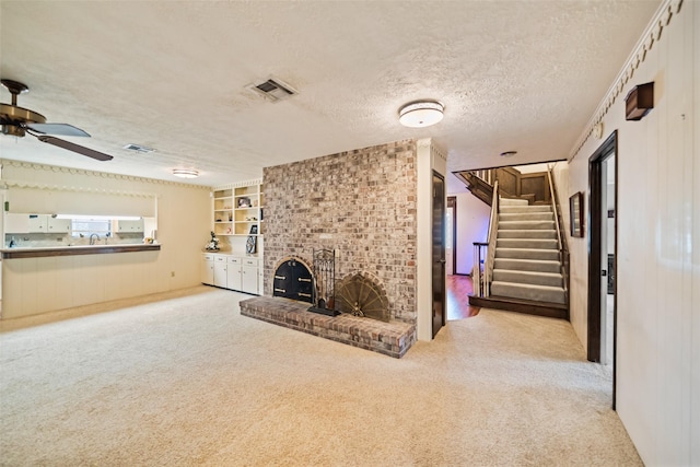 2709 Cherry Ln, Pasadena, TX 77502 - unfurnished living room with carpet, ceiling fan, stairway, a fireplace, and a textured ceiling