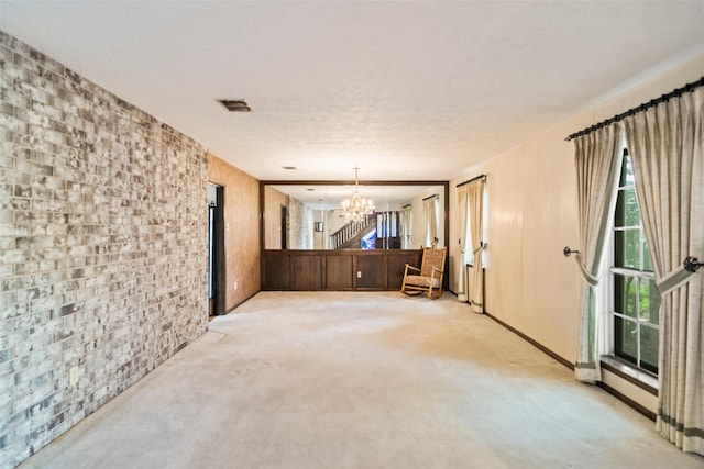 2709 Cherry Ln, Pasadena, TX 77502 - unfurnished room with a chandelier, light colored carpet, and brick wall