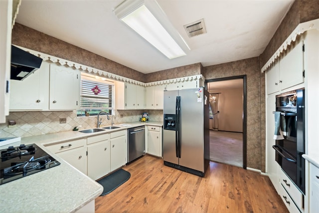 2709 Cherry Ln, Pasadena, TX 77502 - kitchen with black appliances, under cabinet range hood, a sink, light wood-style flooring, and light countertops