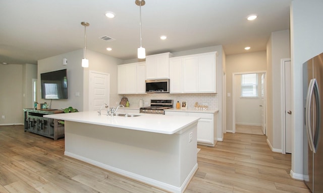 108 Clay Creek Ln, Conroe, TX 77316 - kitchen featuring appliances with stainless steel finishes, a sink, decorative backsplash, light wood-style flooring, and white cabinetry