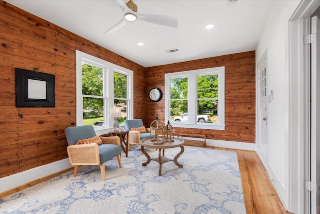 1604 S Austin St, Brenham, TX 77833 - living area with wood finished floors, healthy amount of natural light, baseboards, wooden walls, and a ceiling fan