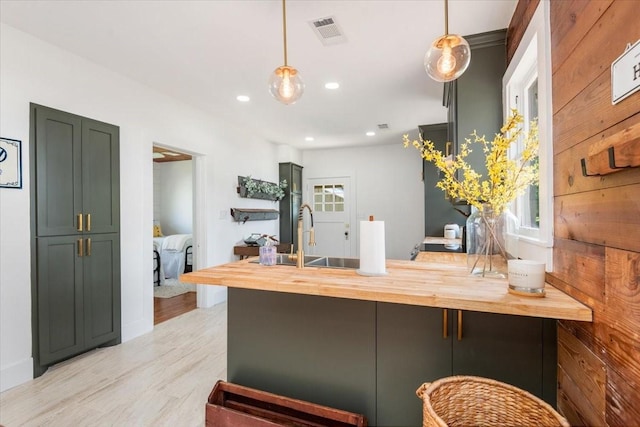 1604 S Austin St, Brenham, TX 77833 - kitchen with butcher block countertops, a peninsula, a sink, light wood-style flooring, and pendant lighting