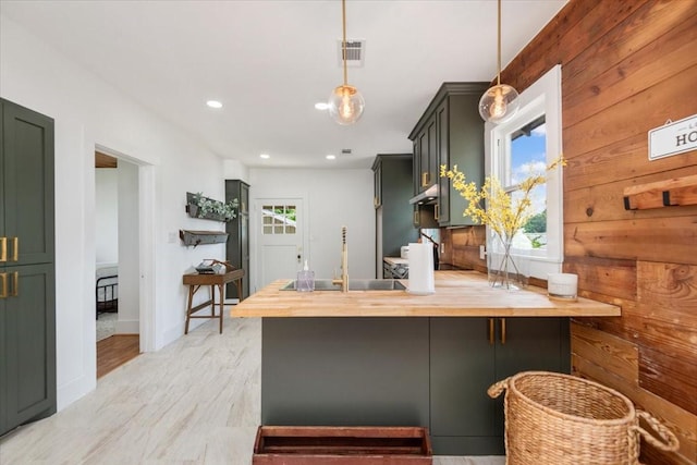 1604 S Austin St, Brenham, TX 77833 - kitchen featuring a sink, butcher block counters, a peninsula, green cabinetry, and hanging light fixtures