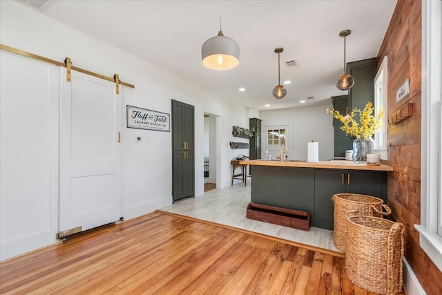 1604 S Austin St, Brenham, TX 77833 - kitchen with light wood finished floors, a barn door, a peninsula, pendant lighting, and recessed lighting