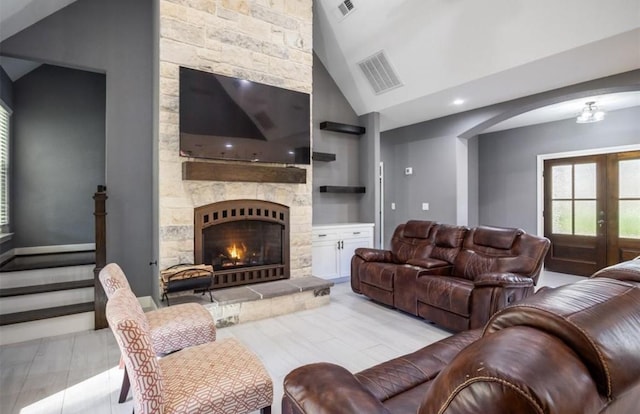 148 Wagon Pass Dr, Huntsville, TX 77340 - living area with a stone fireplace, vaulted ceiling, stairway, french doors, and arched walkways