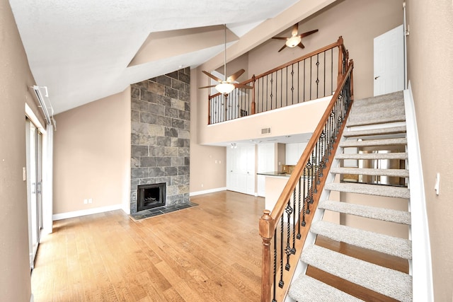 2300 Old Spanish Trl Unit 2078, Houston, TX 77054 - stairs with a ceiling fan, wood finished floors, a tile fireplace, baseboards, and high vaulted ceiling