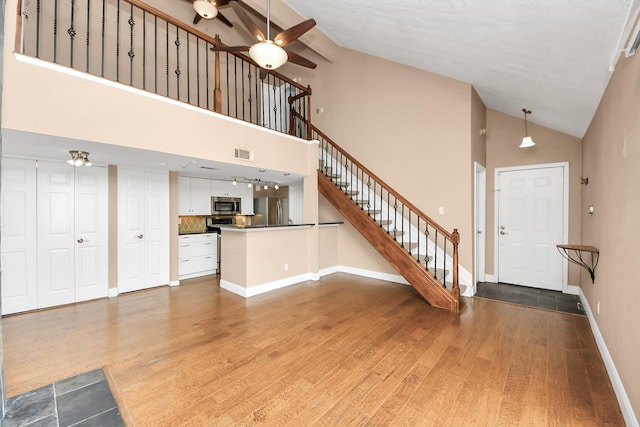 2300 Old Spanish Trl Unit 2078, Houston, TX 77054 - unfurnished living room with ceiling fan, high vaulted ceiling, stairway, wood finished floors, and baseboards
