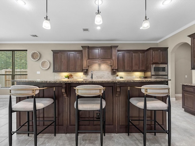 20722 Lavone Dr, Porter, TX 77365 - kitchen with arched walkways, decorative backsplash, dark brown cabinets, ornamental molding, and decorative light fixtures