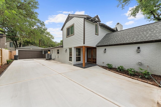 10714 Deerwood Rd, Houston, TX 77042 - rear view of property with concrete driveway, brick siding, a chimney, french doors, and a shingled roof